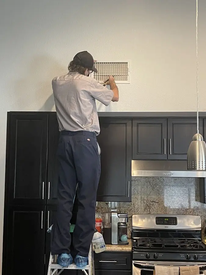 Technician inspecting an air vent during HVAC service in Lampasas
